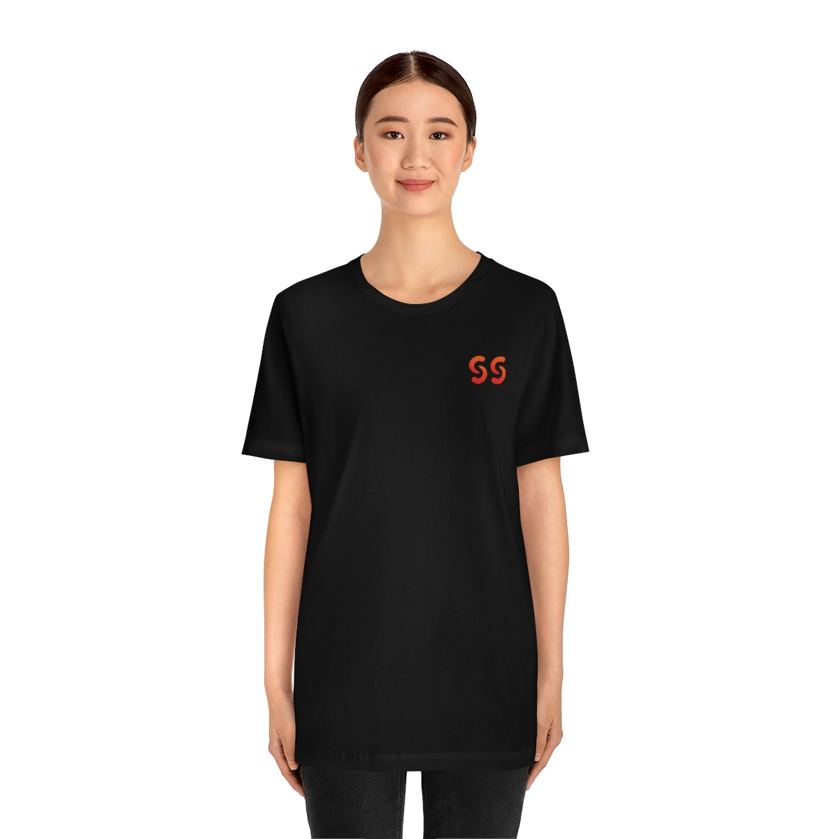 A young light skin tone female model wearing a black t-shirt with stylized "SS" over the left breast denoting sickle cell trait status.
